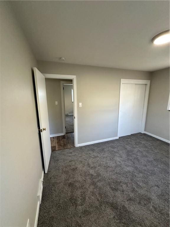 unfurnished bedroom featuring a closet and dark carpet