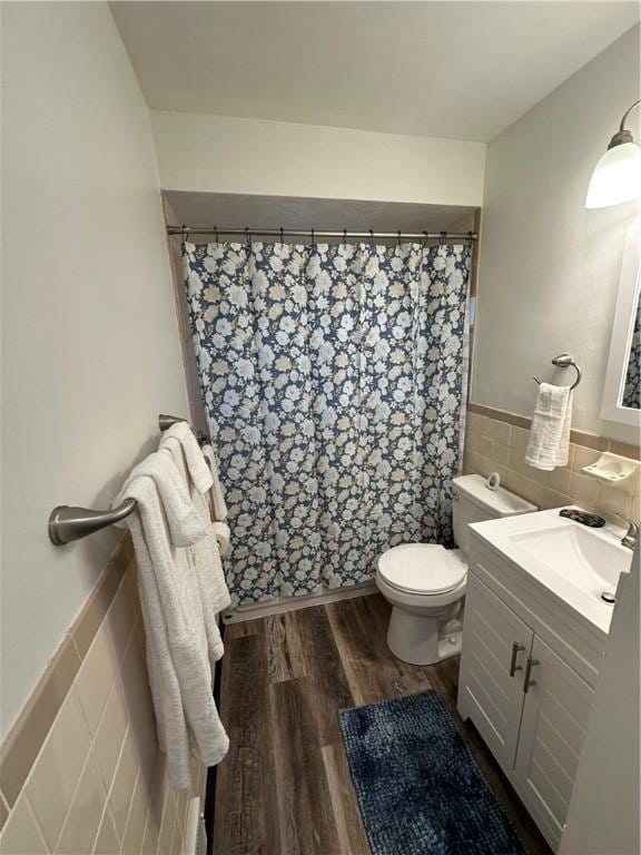 bathroom with toilet, tile walls, wood-type flooring, and vanity