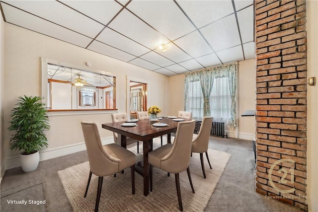 dining room featuring ceiling fan, radiator heating unit, carpet, and a drop ceiling