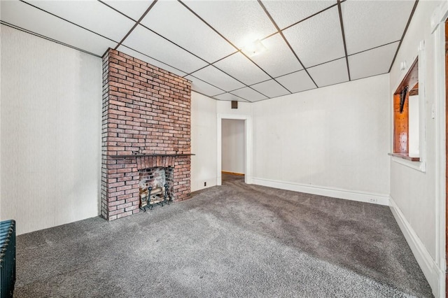 unfurnished living room featuring a drop ceiling, carpet, and a brick fireplace