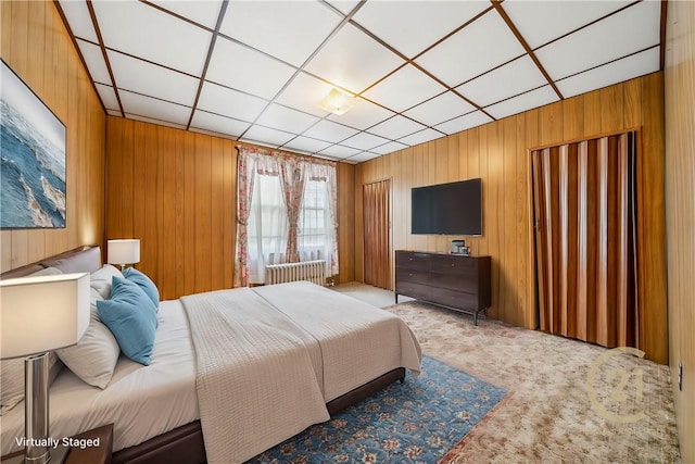 bedroom with light carpet and wooden walls