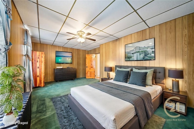 carpeted bedroom with ceiling fan and wood walls