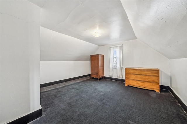 bonus room with dark carpet and lofted ceiling