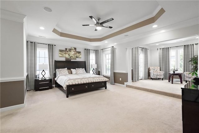 bedroom with a raised ceiling, crown molding, light carpet, and multiple windows