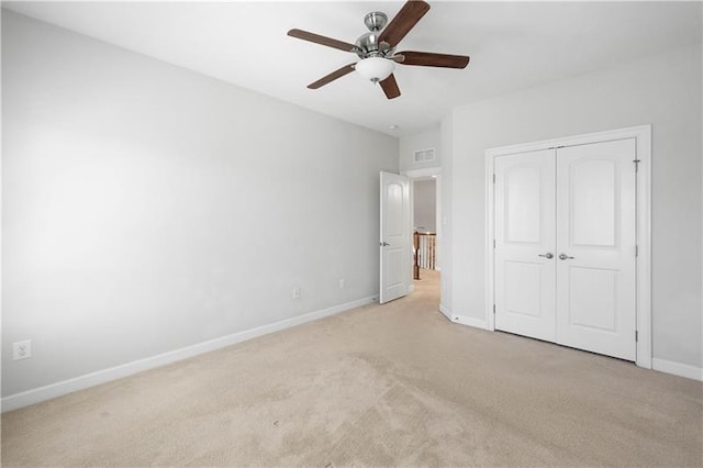 unfurnished bedroom featuring ceiling fan, a closet, and light colored carpet