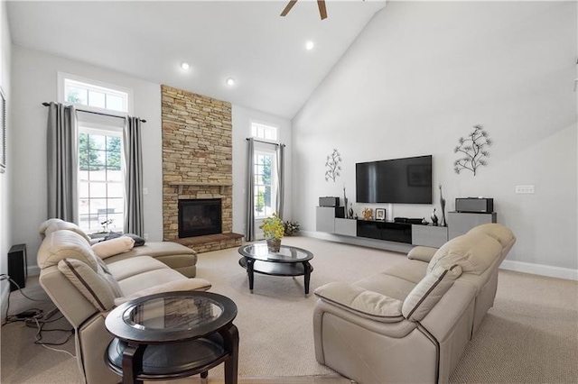 carpeted living room featuring a wealth of natural light, ceiling fan, a stone fireplace, and high vaulted ceiling