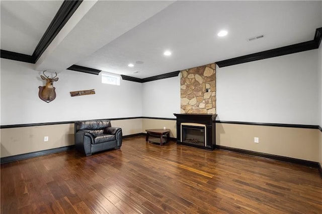 cinema featuring dark hardwood / wood-style flooring, a stone fireplace, and crown molding