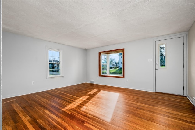 spare room featuring plenty of natural light, a textured ceiling, and hardwood / wood-style flooring