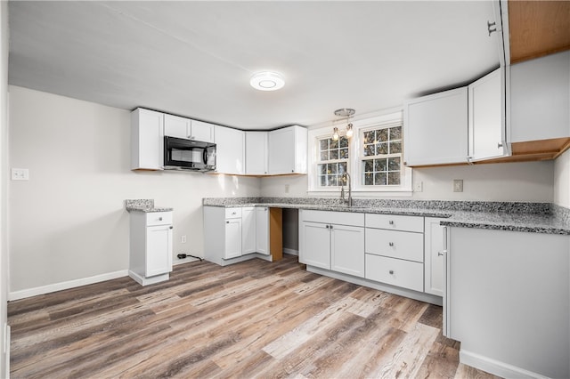 kitchen with light hardwood / wood-style flooring, white cabinetry, hanging light fixtures, and sink