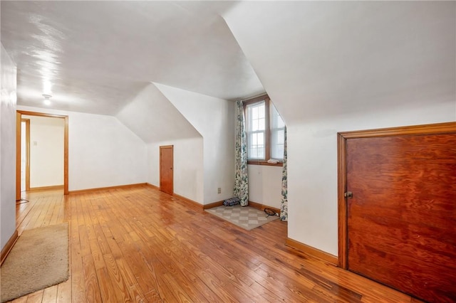 additional living space with light hardwood / wood-style flooring and lofted ceiling