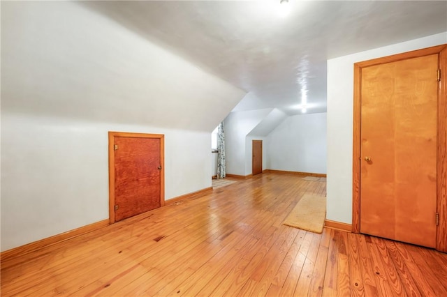 additional living space with vaulted ceiling and light hardwood / wood-style flooring