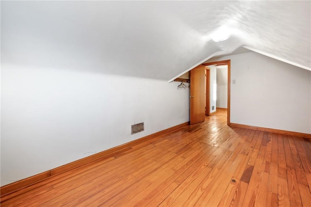 additional living space featuring vaulted ceiling and light wood-type flooring