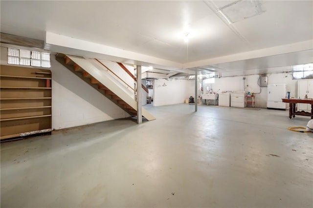 basement featuring electric panel, sink, white fridge, and washing machine and clothes dryer