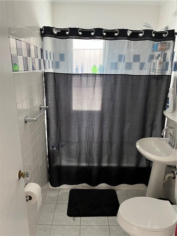 bathroom with tile patterned floors, toilet, tile walls, and walk in shower