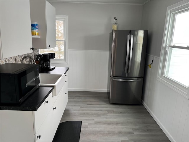 kitchen with stainless steel refrigerator, a wealth of natural light, and white cabinets