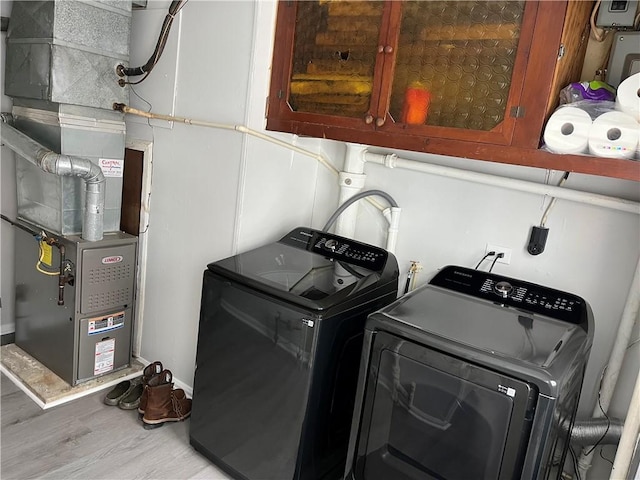 washroom with independent washer and dryer, heating unit, cabinets, and hardwood / wood-style flooring