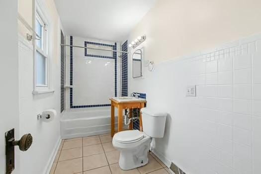 bathroom with tile patterned flooring, plenty of natural light, toilet, and tiled shower / bath