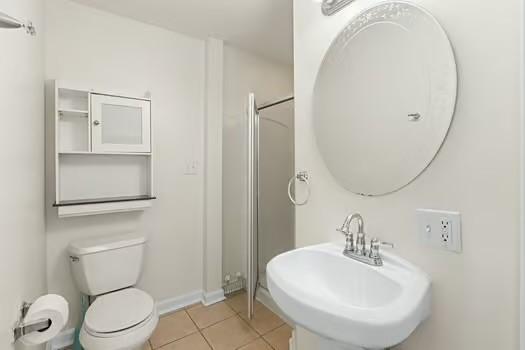 bathroom featuring tile patterned flooring, toilet, sink, and walk in shower