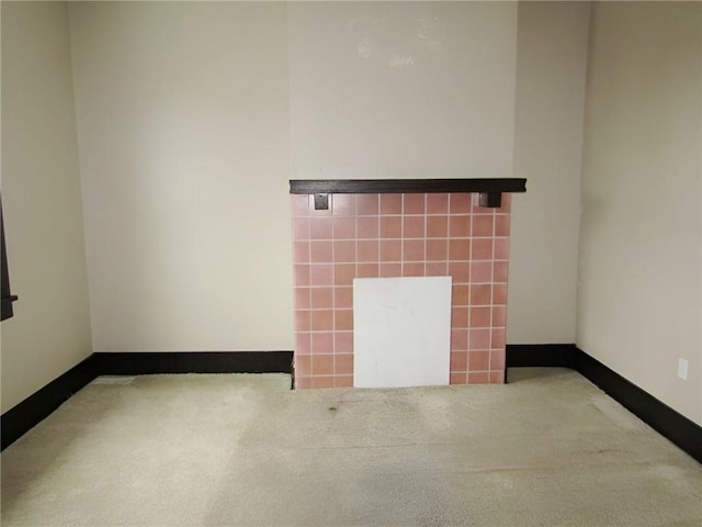 carpeted empty room with a fireplace and tile walls