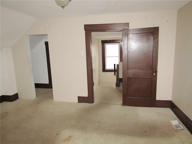 corridor with light colored carpet and vaulted ceiling