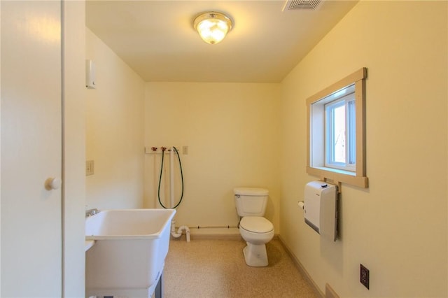 bathroom with heating unit, toilet, and sink