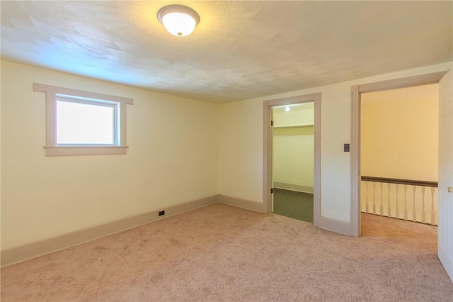 unfurnished bedroom with light carpet, a spacious closet, and a closet