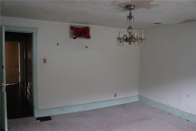 carpeted empty room with a chandelier