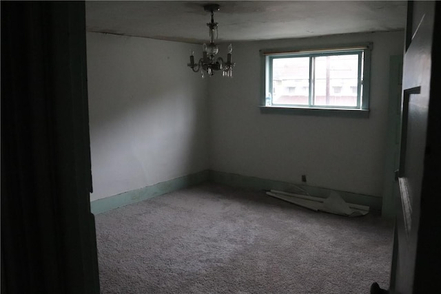 carpeted spare room with a chandelier