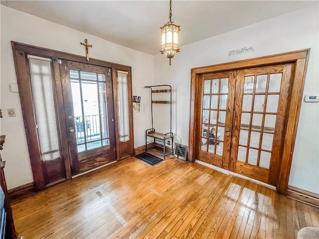 entryway featuring french doors, hardwood / wood-style floors, and an inviting chandelier