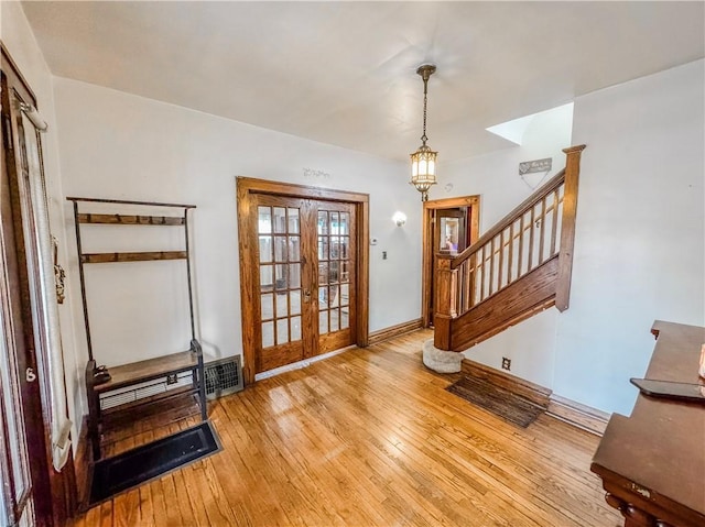 foyer entrance featuring french doors, a baseboard heating unit, and light wood-type flooring