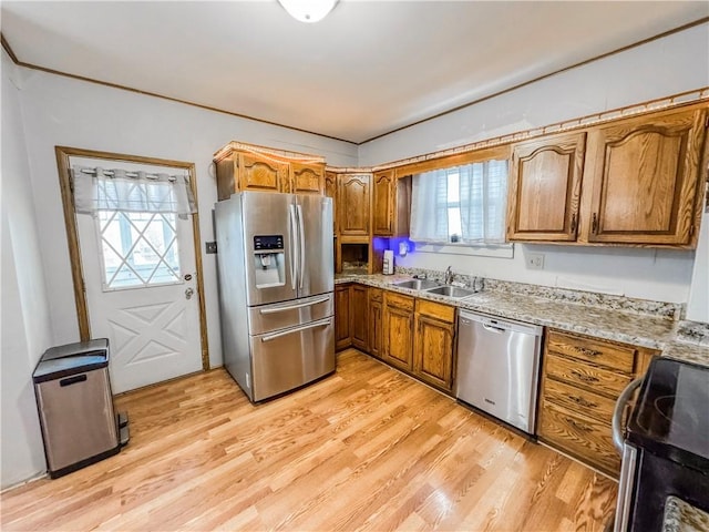 kitchen with light hardwood / wood-style floors, light stone countertops, sink, and appliances with stainless steel finishes