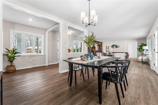 dining area with dark hardwood / wood-style flooring, baseboard heating, and a chandelier