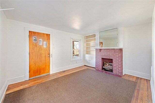 unfurnished living room with hardwood / wood-style floors and a brick fireplace