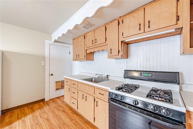 kitchen featuring light wood-type flooring, sink, light brown cabinetry, and range with gas cooktop