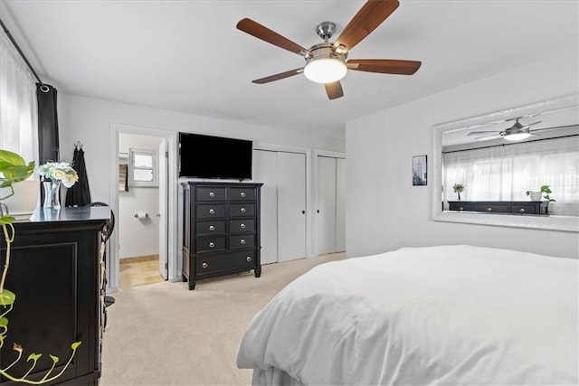 bedroom with ceiling fan, light colored carpet, and two closets