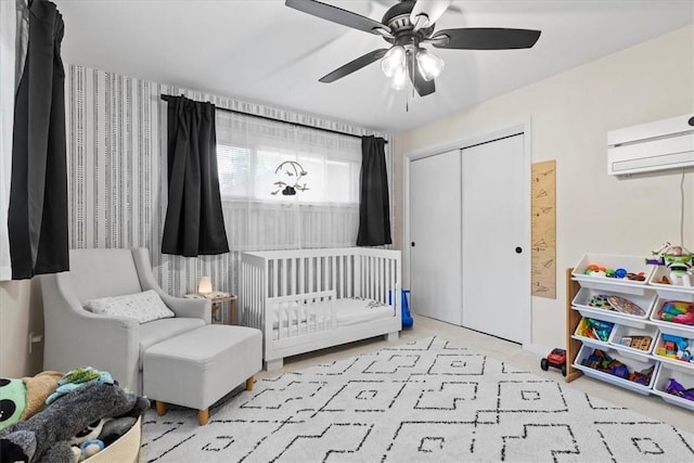 bedroom featuring ceiling fan, a closet, a nursery area, and a wall mounted air conditioner