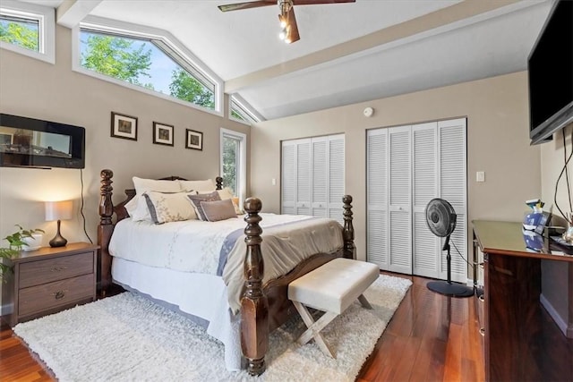 bedroom featuring vaulted ceiling with beams, ceiling fan, dark hardwood / wood-style floors, and two closets