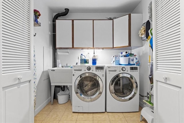 laundry room featuring washer and dryer, light tile patterned flooring, and cabinets