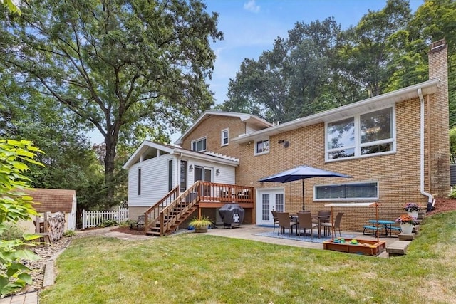 rear view of property featuring a lawn, a patio area, and a deck