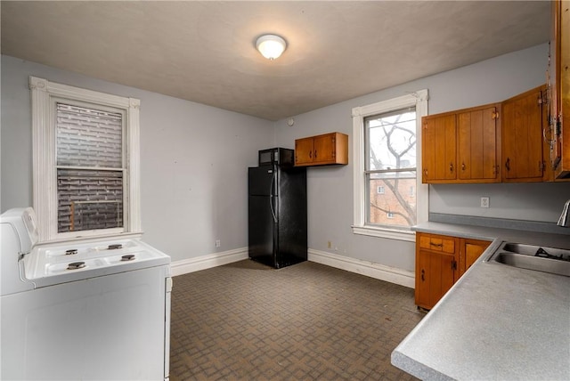 kitchen featuring washing machine and clothes dryer, sink, and black appliances