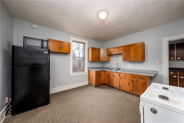 kitchen featuring black refrigerator, sink, and electric stove