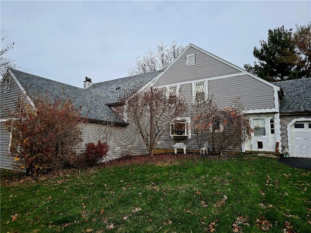 rear view of house featuring a garage and a lawn