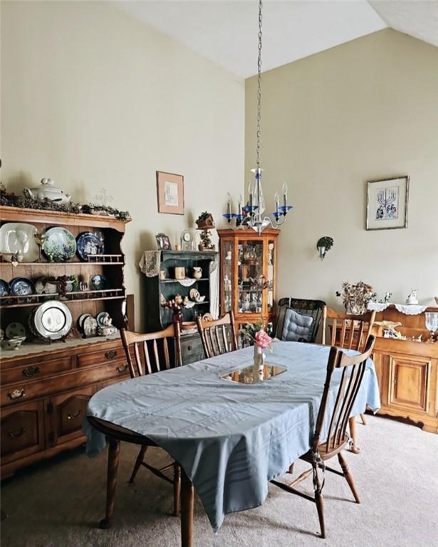 carpeted dining space with lofted ceiling