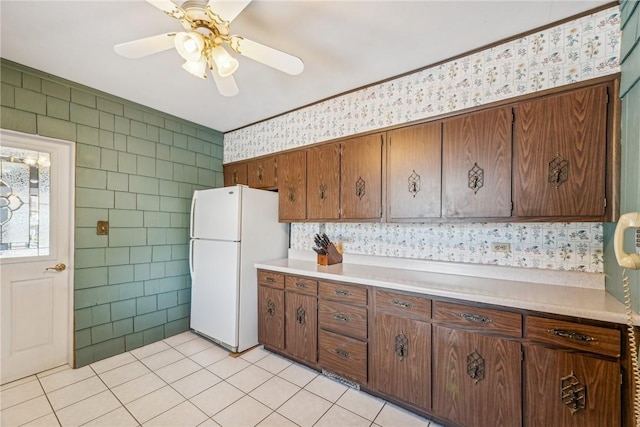 kitchen with tile walls, ceiling fan, white fridge, and light tile patterned floors