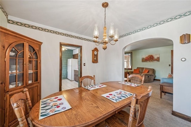 dining space with light carpet and an inviting chandelier