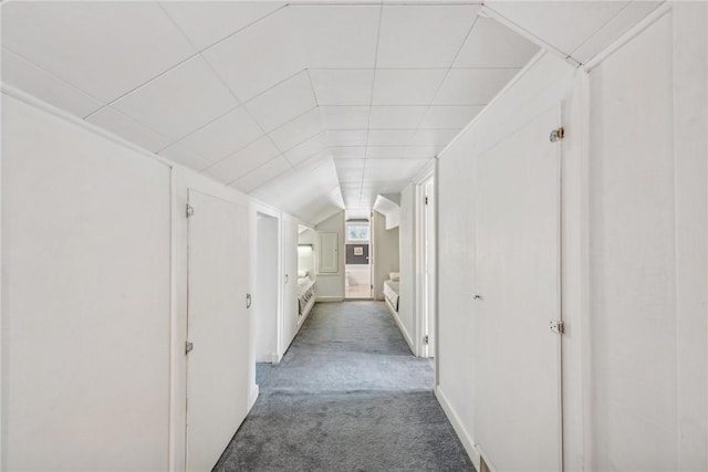 corridor featuring dark colored carpet and vaulted ceiling