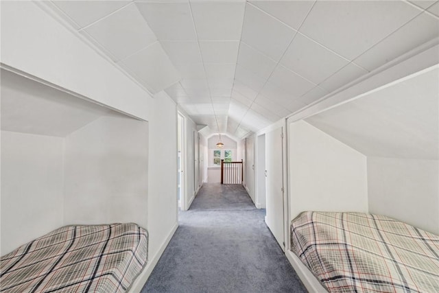 hallway featuring dark colored carpet and vaulted ceiling