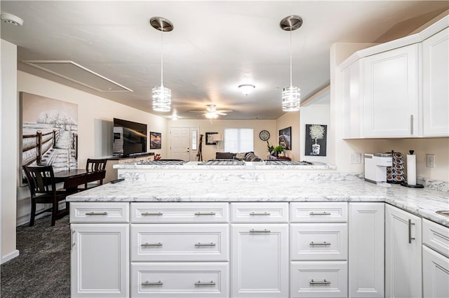 kitchen with ceiling fan, light stone counters, pendant lighting, white cabinets, and dark carpet