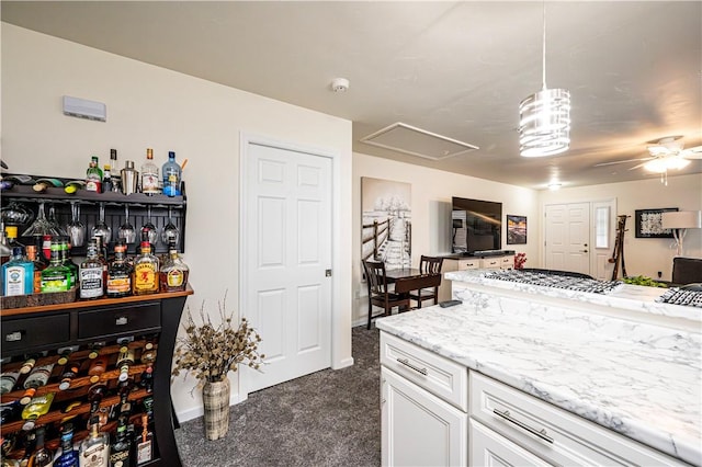 kitchen with dark carpet, light stone counters, ceiling fan, pendant lighting, and white cabinetry