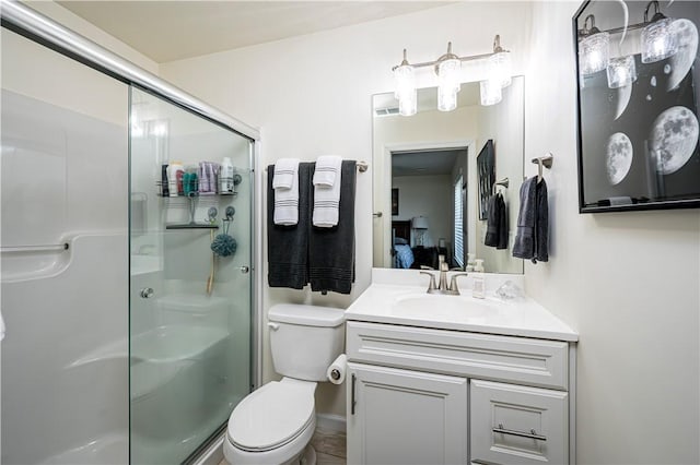 bathroom with a shower with door, vanity, and toilet